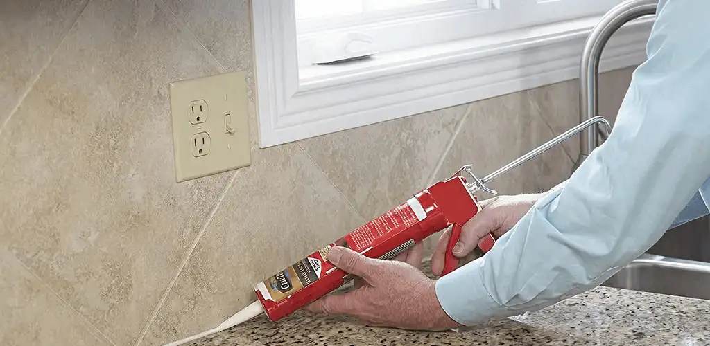 Handyman applying caulk along a kitchen backsplash and countertop seam in San Francisco, CA