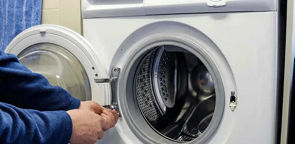 Washing machine repair handyman checking a front-load washer door and latch in San Francisco, CA