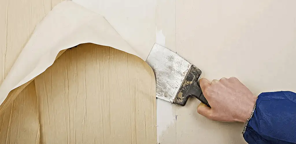 Handyman removing wallpaper with a scraper for wall preparation in San Francisco, CA