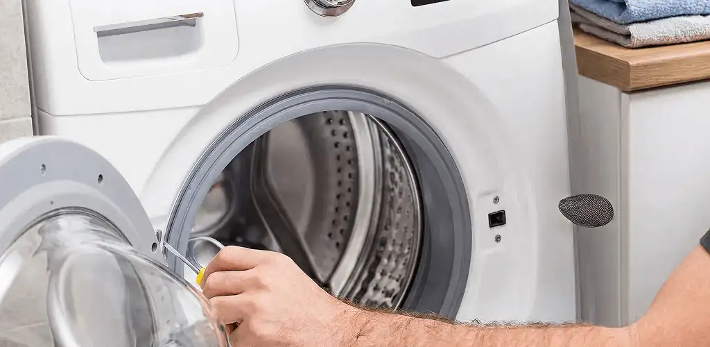 Handyman repairing a front-load washing machine and inspecting the drum in San Francisco, CA